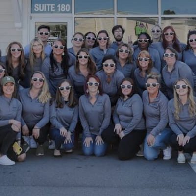 Group photo of women in matching gray hoodies and sunglasses.